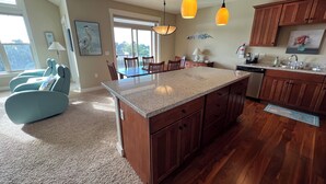 A spacious kitchen with wooden cabinets, a granite countertop, and pendant lighting. - BP 410 River Song Condo.  3 blocks from the beach (Seaside)