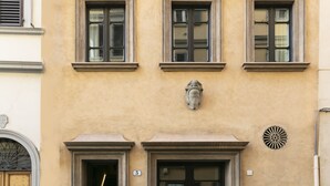 Une façade d’immeuble avec trois fenêtres, une porte et un élément décoratif mural.