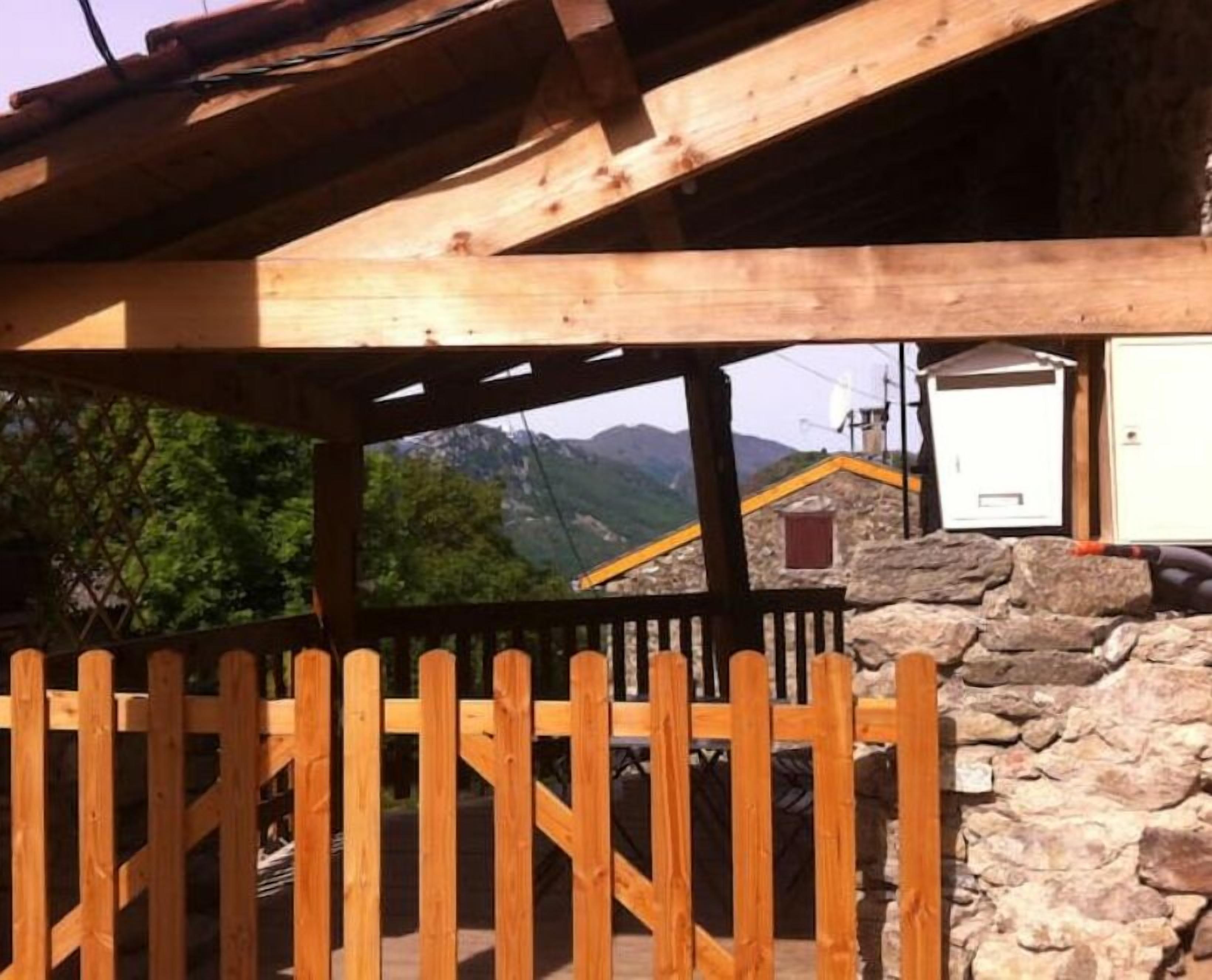 Una estructura de madera con un muro de piedra, una valla de madera y vistas a montañas.