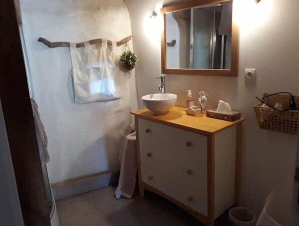 Un baño con tocador de madera, un espejo grande, un lavabo blanco y un perchero para toallas.