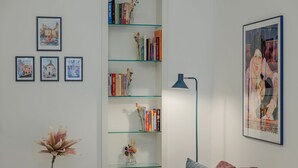 Un salón con una estantería de vidrio, un cuadro enmarcado y un florero con flores.