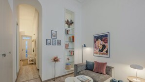 Una sala moderna con un sofá gris, una mesita redonda, una estantería y una obra de arte enmarcada en la pared.