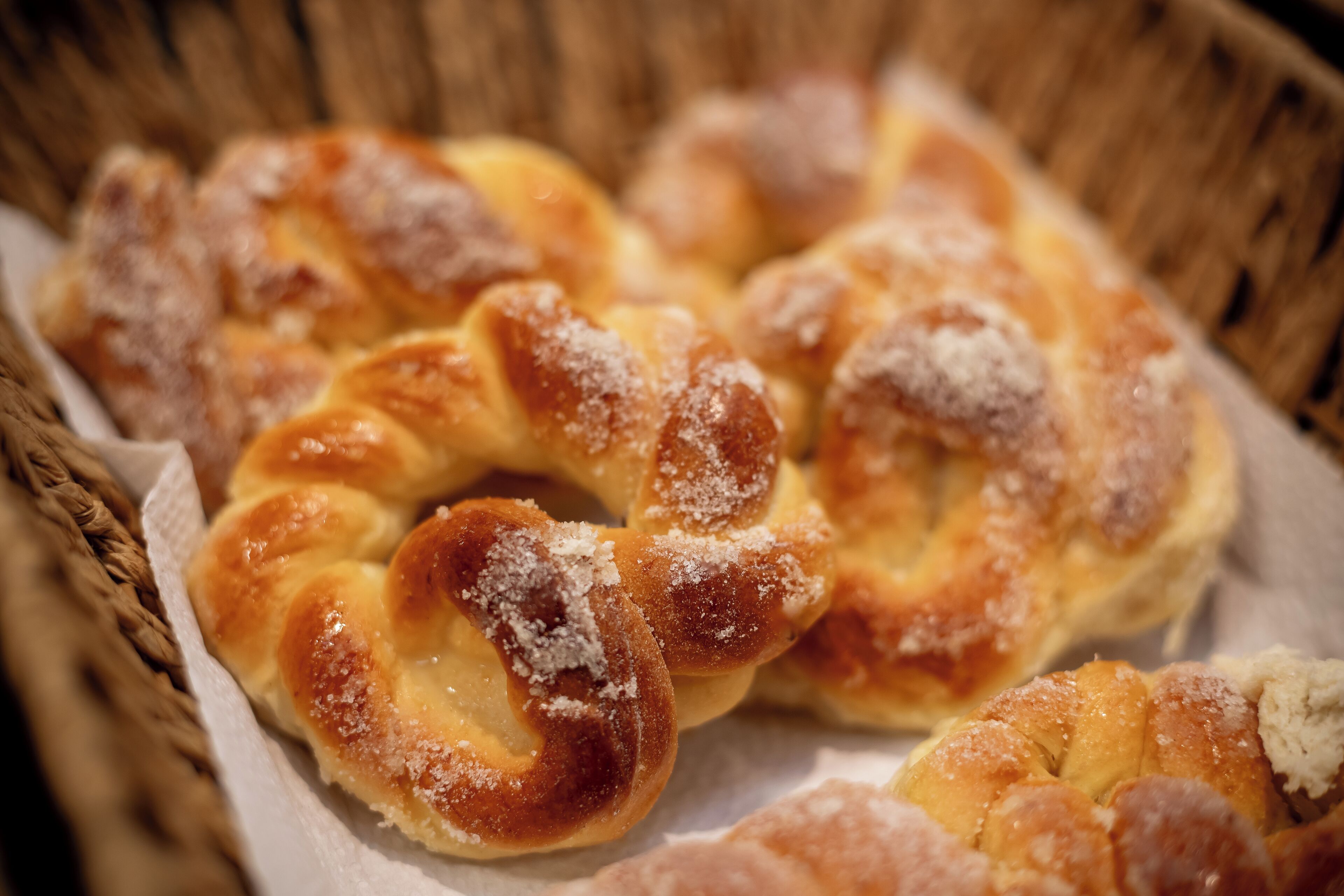 A basket of twisted bread rolls with a dusting of sugar.
