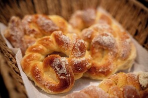A basket of twisted bread rolls with a dusting of sugar. - Augusta Hotel by Samba (Joao Neiva)