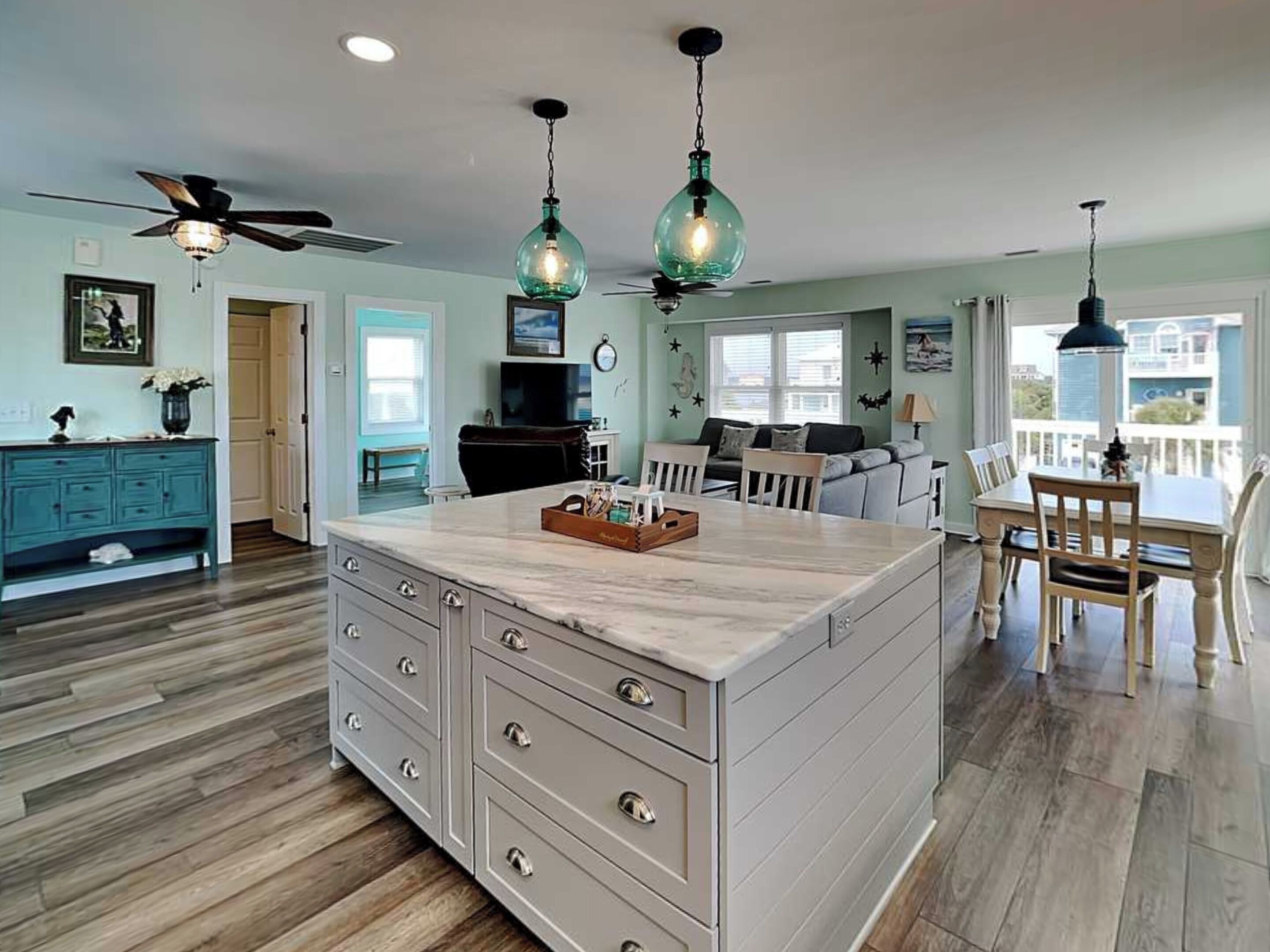 A kitchen with a central island, wooden cabinets, a ceiling fan, and pendant lighting.
