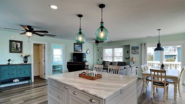 A kitchen with a central island, wooden cabinets, a ceiling fan, and pendant lighting. - The Salty Seahorse | Across from Beach + Views! (North Topsail Beach)