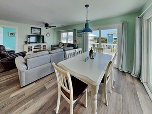 Sala de estar con sofá, televisión, ventilador de techo, mesa de comedor y sillas.