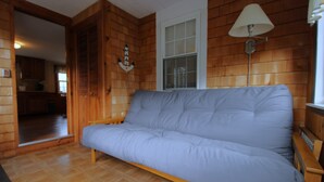 Ett rum med träinredning, en soffa, en lampa och en dörr som leder in till ett kök.