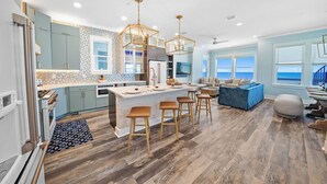 A modern kitchen with a central island, bar stools, and a dining area with a view of the ocean. - "Shore Thing" Brand New Beachfront Rental Home in Panama City Beach - Perfect for Group Getaway! (Panama City)
