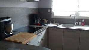 A modern kitchen with a coffee maker, a cutting board, and a sink. - Loue Maison Individuelle (Bénodet)