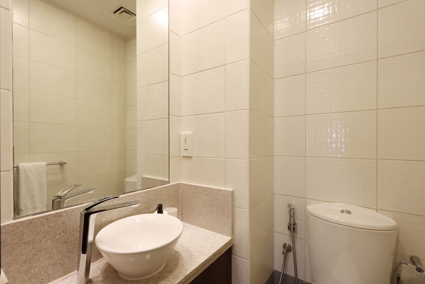 A bathroom with a white sink, mirror, and toilet.