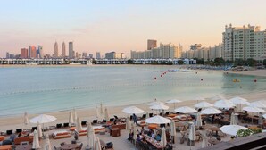 A coastal hotel with outdoor seating, a view of the beach, and a city skyline in the background. - Seaside Studio in PalmJumeirah,Beach Access (Dubai)