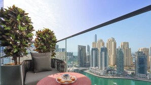 A balcony with a city view, a round table with a drink, and two potted plants.