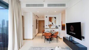 Un salón moderno con comedor, televisor de pantalla plana y vistas a la ciudad.