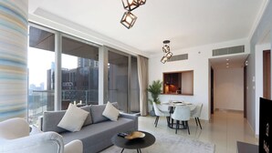 Een moderne woonkamer met een bank, eettafel, stoelen, grote ramen en uitzicht over de stad.