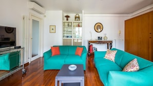 A living room with teal sofas, a coffee table, and a television. - Colonna Classic Style Apartment by Wonderful Italy (Naples)
