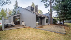 Ett modernt hus med en veranda, en skorsten av sten och en stor glasdörr.