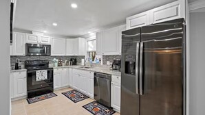 Una cocina moderna con gabinetes blancos, electrodomésticos de acero inoxidable y encimera de granito.