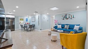 Una sala moderna con un sofá azul, un sillón amarillo y un comedor con mesa y sillas.