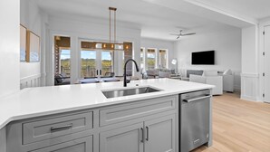 A modern kitchen with a large island, white cabinetry, and a built-in dishwasher. - Golf Cart | Near Private Beach Access (Watersound)