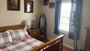 Un dormitorio con cama de madera, cómoda, espejo y ventana con cortinas.