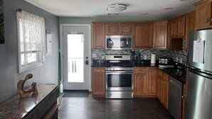 Una cocina moderna con armarios de madera, electrodomésticos de acero inoxidable y una encimera negra.