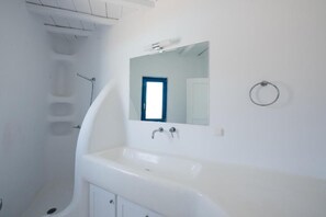 Une salle de bain moderne avec un grand lavabo blanc, un miroir et une douche.
