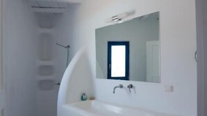 Un bagno con lavandino bianco, specchio e doccia.