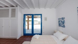 Una camera da letto con un letto, un armadio, una porta che dà su una zona esterna e una parete decorata con un'opera d'arte floreale blu.