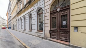A street view with a building featuring a large wooden door and arched windows. - Venus Apartments - Opera III (Budapest)