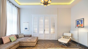 A modern living room with a sectional sofa, a chaise lounge, a coffee table, and a floor lamp. - Venus Apartments - Opera III (Budapest)