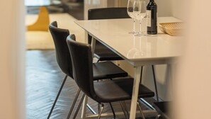 A dining area with a table, chairs, a bottle, and glasses. - Venus Apartments - Opera III (Budapest)
