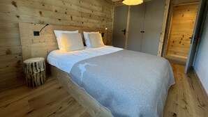 Puupaneloitu makuuhuone, jossa on sänky, yöpöytälamppu ja vaatekaappi.