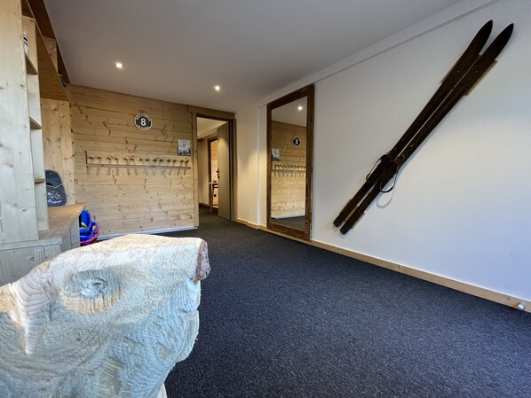 A hotel corridor with a wooden wall, a mirror, and a pair of skis leaning against the wall.