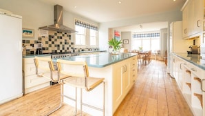 A spacious kitchen with a large island, wooden flooring, and modern appliances.