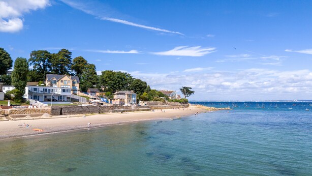 A coastal beach with houses and clear blue water.
