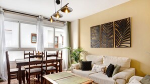 Una sala de estar con una mesa de comedor, sillas, un sofá y una mesa de centro.