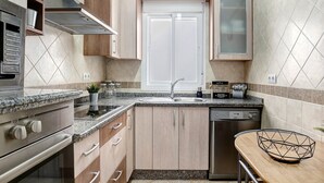Una cocina moderna con encimeras de granito, electrodomésticos de acero inoxidable, armarios de madera y lavavajillas integrado.