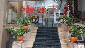 Eine Treppe führt zu einem Hauseingang, gesäumt von Kübelpflanzen und traditioneller Dekoration.