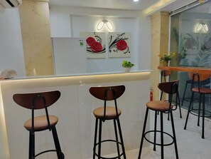 Eine moderne Bar mit drei Hockern und zwei Wandleuchten.