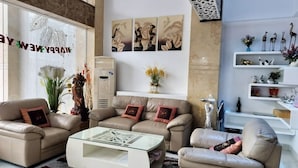 Ein modernes Wohnzimmer mit einem beigefarbenen Sofa, einem Glastisch und Dekorationen auf Regalen.