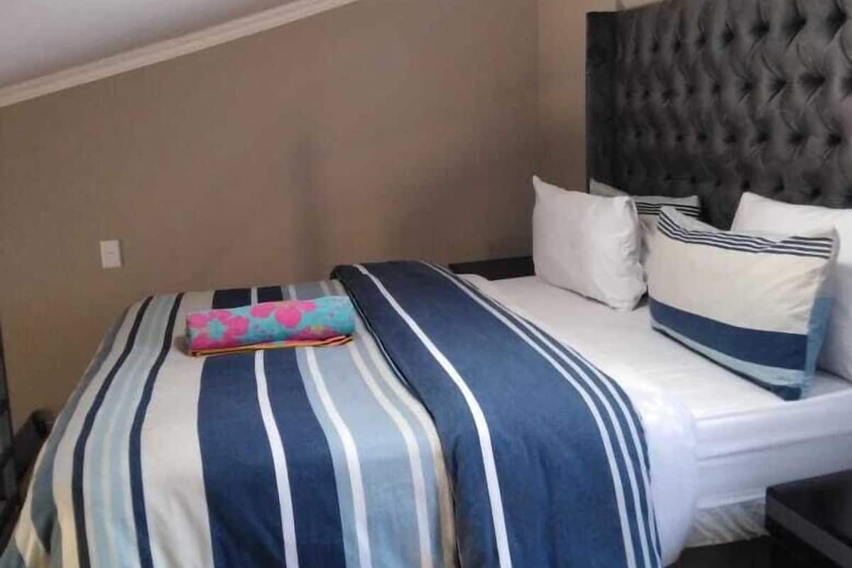 A bedroom with a bed, a headboard, and a bedside table.