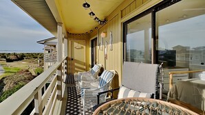 A balcony with wicker chairs and a table, overlooking a beach and ocean. - Lighthouse Point 7C | Easy Access to Pool & Beach! (Tybee Island)