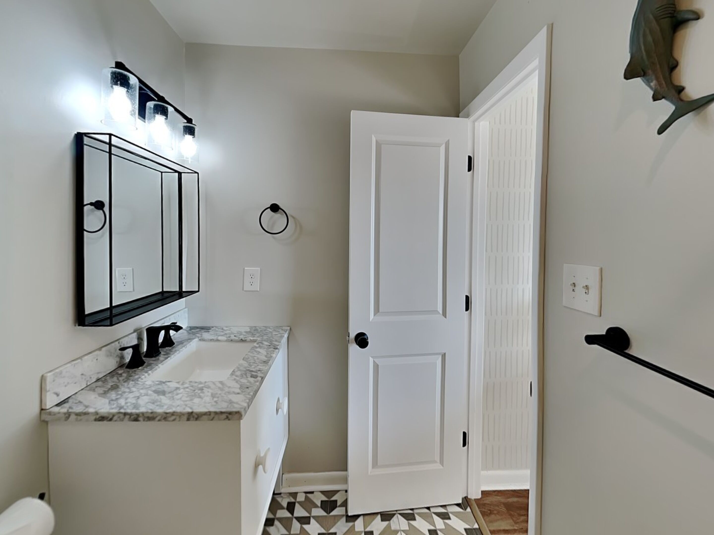 A bathroom with a white vanity, a mirror, and a towel rack.