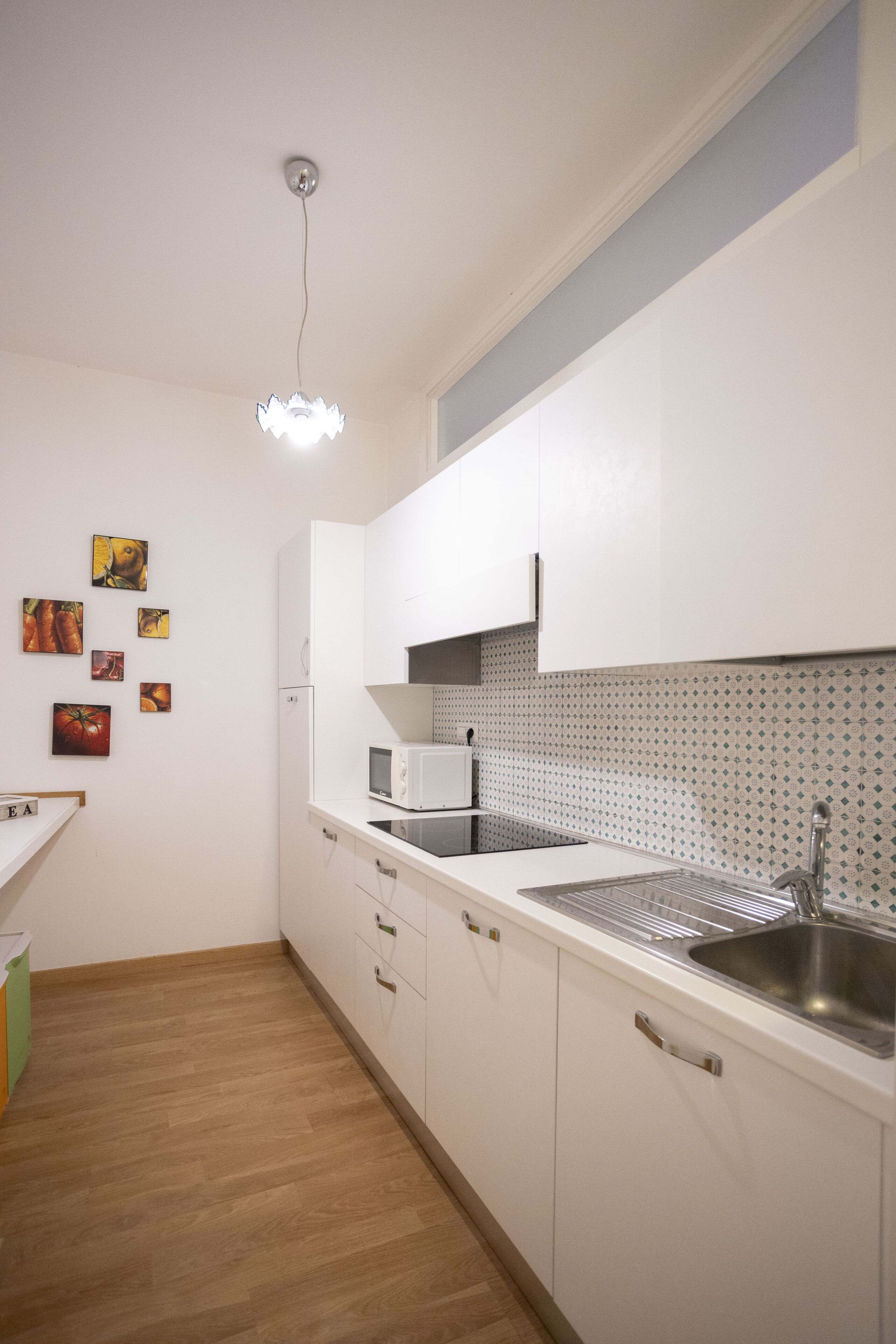 A modern kitchen with white cabinets, a stainless steel sink, and a microwave.