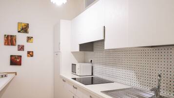 A modern kitchen with white cabinets, a stainless steel sink, and a microwave.