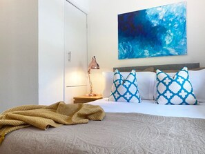 Une chambre d’hôtel avec un lit, une table de chevet, une lampe et un grand tableau abstrait accroché au mur.