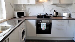 Una cocina compacta equipada con lavadora, microondas, estufa, horno y lavaplatos.