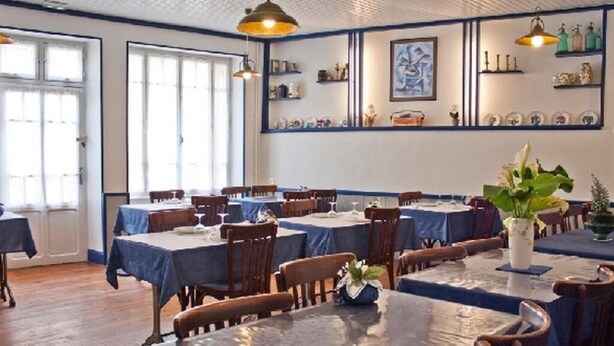A dining area with tables set for multiple people, wooden chairs, and blue tablecloths. - Hôtel Magne (Saurier)