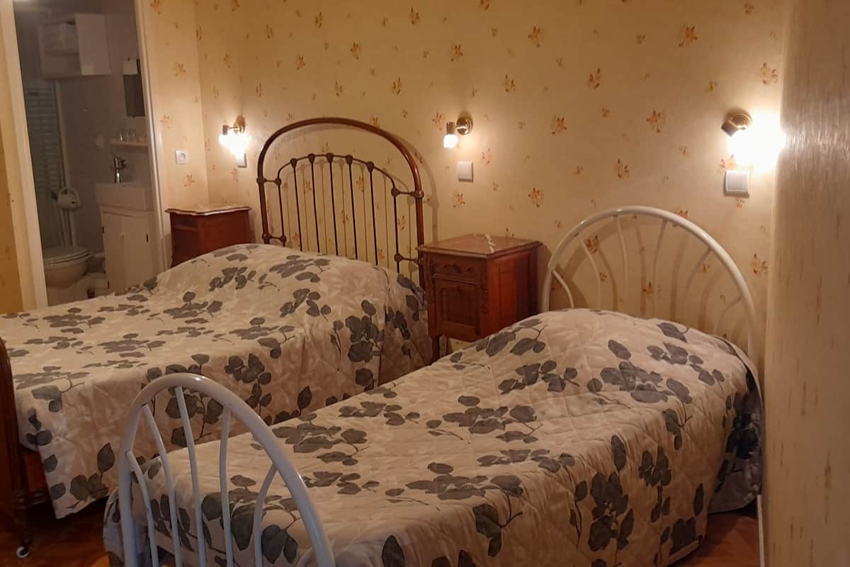 Un dormitorio con dos camas individuales, una mesita de noche de madera, un aparador y un espejo.